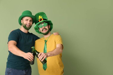 Yeşil sakallı cüce şapkalı genç adamlar yeşil arka planda bira şişeleri taşıyorlar. Aziz Patrick Günü kutlaması