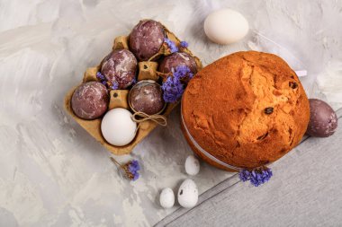 Lezzetli Paskalya pastası, gri arka planda boyanmış yumurta ve çiçekler.