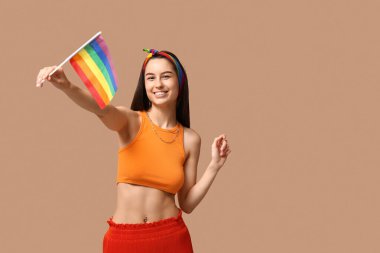 Göbeğinde piercing ve arka planında LGBT bayrağı olan genç ve güzel bir kadın.