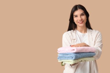 Kahverengi arka planda temiz havluları olan güzel genç bir kadın.