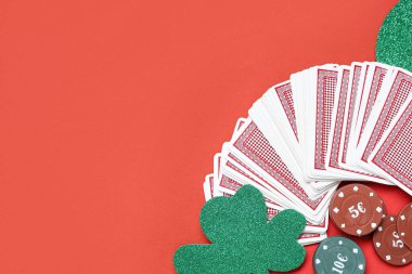 Kartlı poker fişleri ve kırmızı arka planda şanslı yonca. Aziz Patrick Günü kutlaması