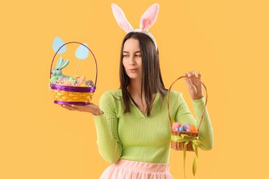 Tavşan kulaklı düşünceli genç bir kadın. Sarı arka planda Paskalya yumurtaları var.