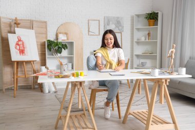 Atölyedeki kadın Asyalı sanatçı çizim yapıyor.