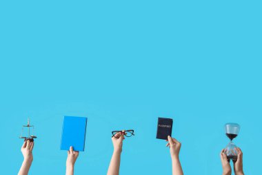 Kum saati tutan kadın eller, adalet terazisi, pasaport ve mavi arka plan üzerine kitap.