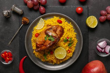 Siyah arka planda malzemelerle geleneksel tavuk biryani tabağı.