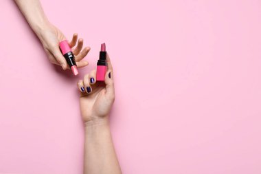 Pembe arka planda ruj izi olan kadın elleri.