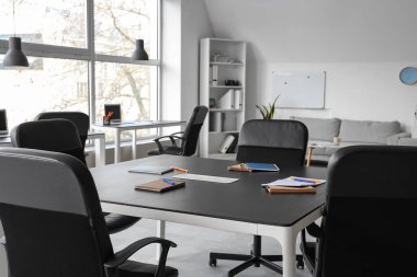 Masalar, koltuklar ve kırtasiye şık bir konferans salonunda yapılacak iş toplantısı için hazırlanıyor.