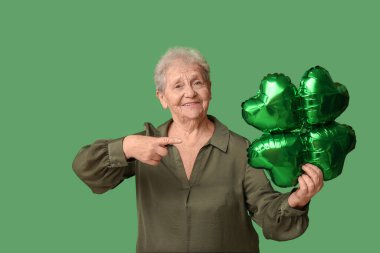 Yeşil arka planda yonca şeklinde hava balonunu gösteren yaşlı kadın. Aziz Patrick Günü kutlaması