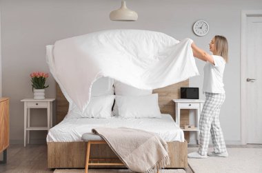 Yatak odasında yatak hazırlayan güzel bir genç kadın.