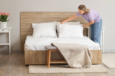 Yatak odasında yastığı koyan güzel bir genç kadın.