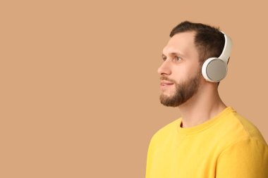 Kahverengi arka planda modern kulaklıklı genç adam.