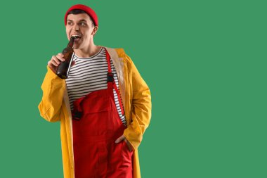 Yeşil arka planda biralı genç denizci.