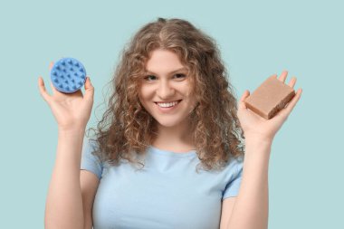 Saç derisi masajcısı ve mavi arka planda şampuan barı olan güzel bir genç kadın.