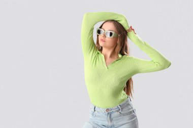 Gri arka planda şık giyinmiş güzel bir kadın.