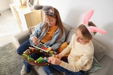 Tavşan kulaklı küçük çocuklar evde Paskalya çelengi yapıyorlar.