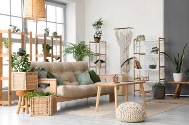 Rahat kanepesi, masası, çiçekleri, rafları ve penceresi olan şık bir oturma odası.