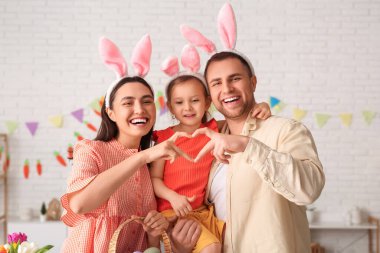 Paskalya tavşanı kulaklarındaki mutlu aile evde elleriyle kalp yapıyor.