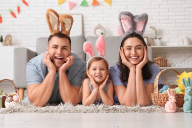 Paskalya hediyeleri evde yerde yatan tavşan kulaklı mutlu bir aile.