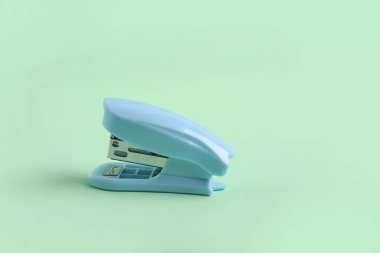Blue stapler on green background