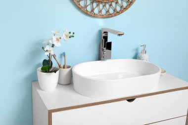 Banyoda mavi duvarın yanında banyo malzemeleri olan modern lavabo.