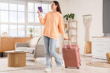Bavullu ve pasaportlu bir kadın turist evde yürüyor.