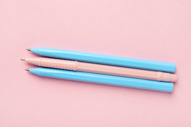 Pembe arka planda üç renkli kalem. Üst görünüm