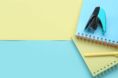 Renk arkaplanında dizüstü, kalem ve zımba içeren kompozisyon