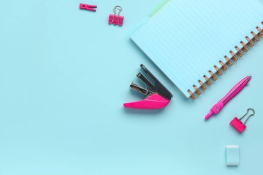 Mavi arka planda zımba, defter, lastik ve klipsli kompozisyonlar