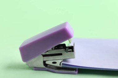 Yeşil arka planda yapışkan notları olan leylak zımba.