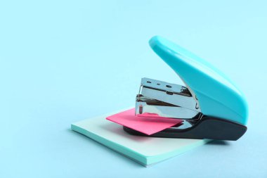 Renk arkaplanı üzerine yapışkan notları olan mavi zımba.