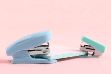 Pembe arka planda yapışkan notları olan mavi zımbalar.