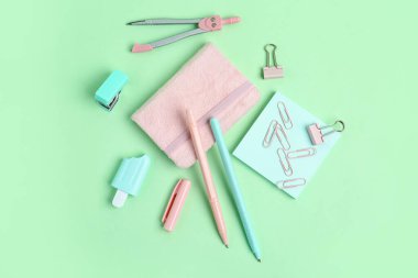 Yeşil arka planda not defteri ve farklı okul sayfası olan kalemler