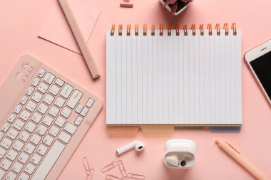 Pembe arka planda defter, klavye ve telefon ile kompozisyon. Üst görünüm