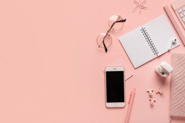 Pembe arka planda not defterleri, gözlükler ve kulaklıklar olan kompozisyon. Üst görünüm