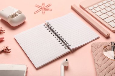 Pembe arka planda not defteri, ataç ve kulaklık ile kompozisyon