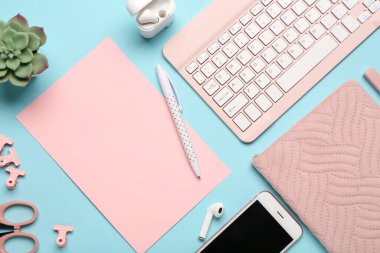 Mavi arka planda pembe kağıt, kalem ve klavye ile kompozisyon. Üst görünüm