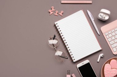 Gri arka planda defter, kalem ve kulaklık olan kompozisyon. Üst görünüm