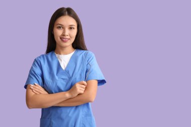 Leylak arka planında diş aletleri olan genç bir dişçi.