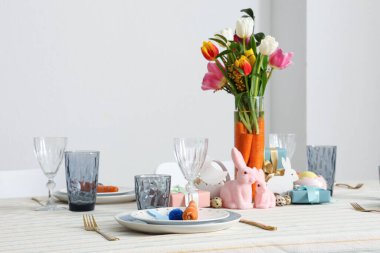 Paskalya için çok güzel bir masa. Beyaz duvara karşı havuç ve çiçeklerle süslenmiş.