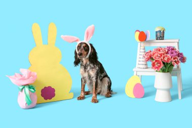 Paskalya pastası ve tavşan kulaklı şirin cocker spaniel, güzel laleler kağıt yumurtalar ve mavi arka planda tavşan