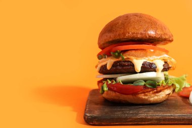 Turuncu arka planda lezzetli burgerli tahta