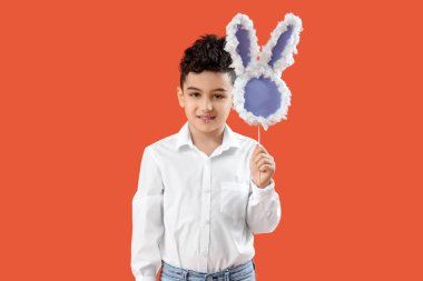 Turuncu arka planda kağıttan tavşan figürlü şirin bir çocuk. Paskalya kutlaması