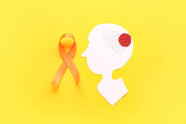 Kağıt insan kafası ve sarı arka planda turuncu kurdele. Çoklu Skleroz Farkındalık Ayı