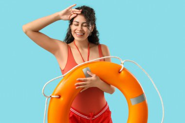 Mavi arka planda halka şamandırası olan güzel, mutlu, Afro-Amerikan kadın cankurtaran.