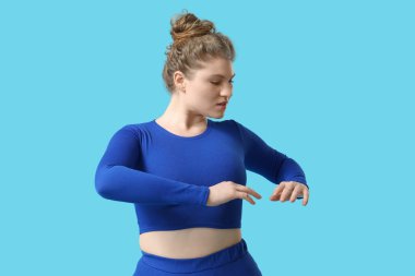 Mavi arka planda gerinen genç bir kadın.