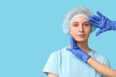 Plastik cerrah mavi arka planda kadının yüzünü inceliyor. Blepharoplasty konsepti