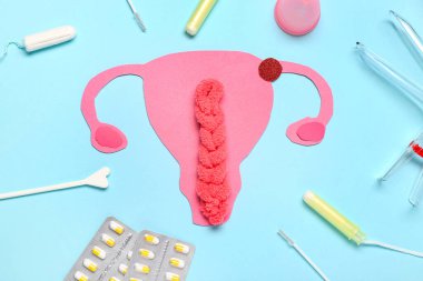 Jinekolojik spekulumlu kağıt rahim, mavi arka planda haplar ve tamponlar.