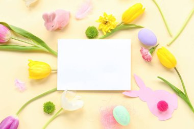 Paskalya yumurtaları, tavşanlar ve bej arkaplanda laleler olan boş bir kart.