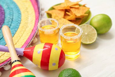 Beyaz arka planda tekila, limon ve marakas, yakın plan.