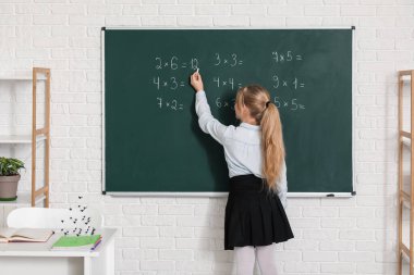 Sınıfta derste tahtaya yazı yazan tatlı kız.